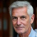 Ritratto di Marco R., un uomo di mezza età con espressione pensosa, in un ambiente accademico.